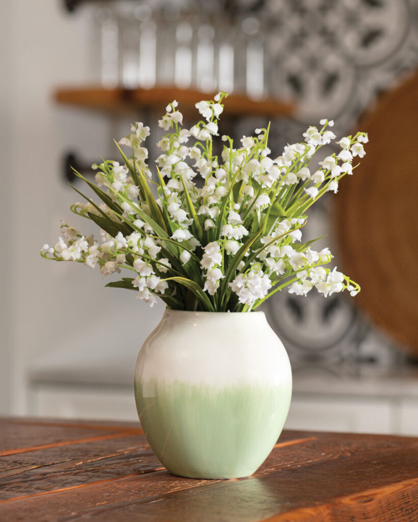 a vase of lily of the valley on top of a wooden table